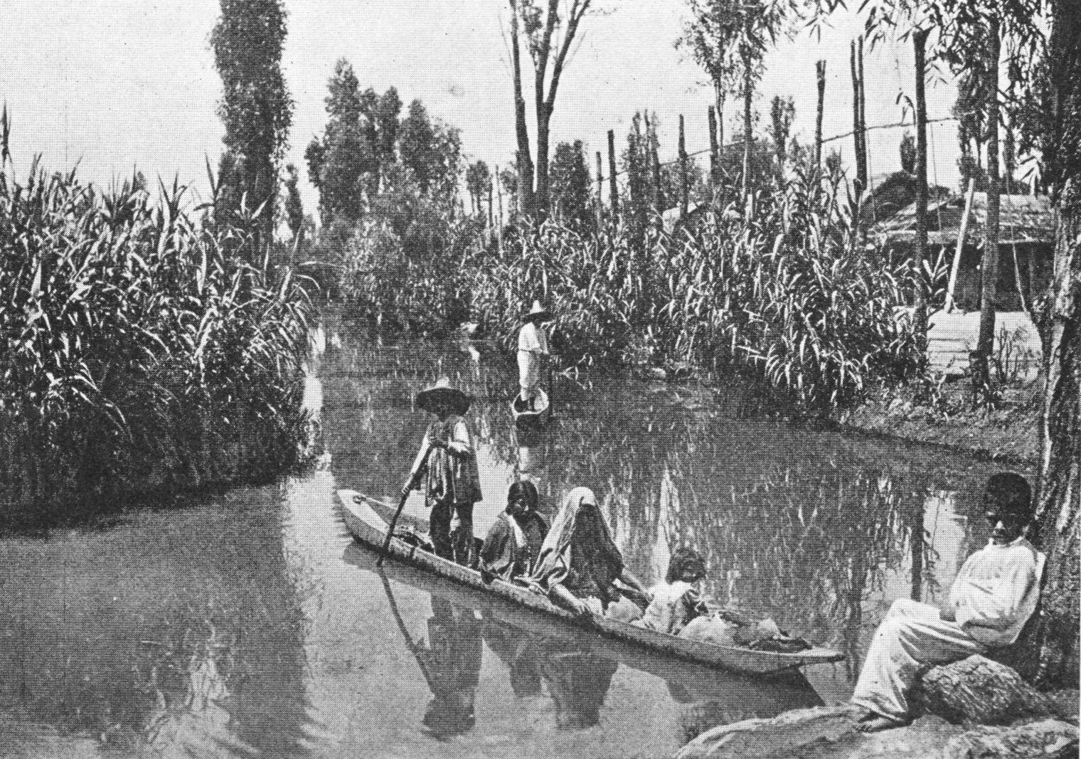 scanned black and white photo of people in a small boat on a canal