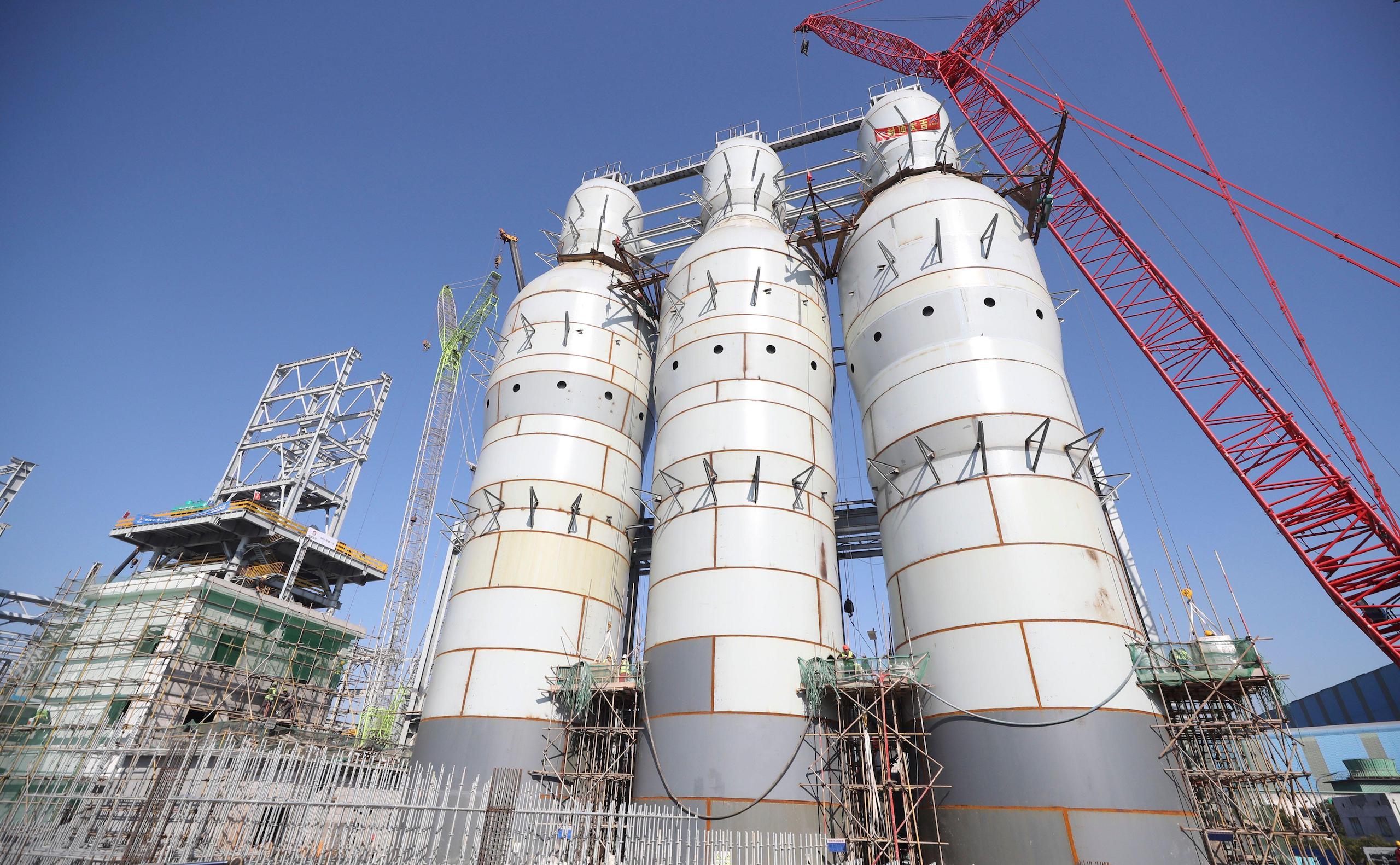 Three white towers in an Industrial facility against a blue sky