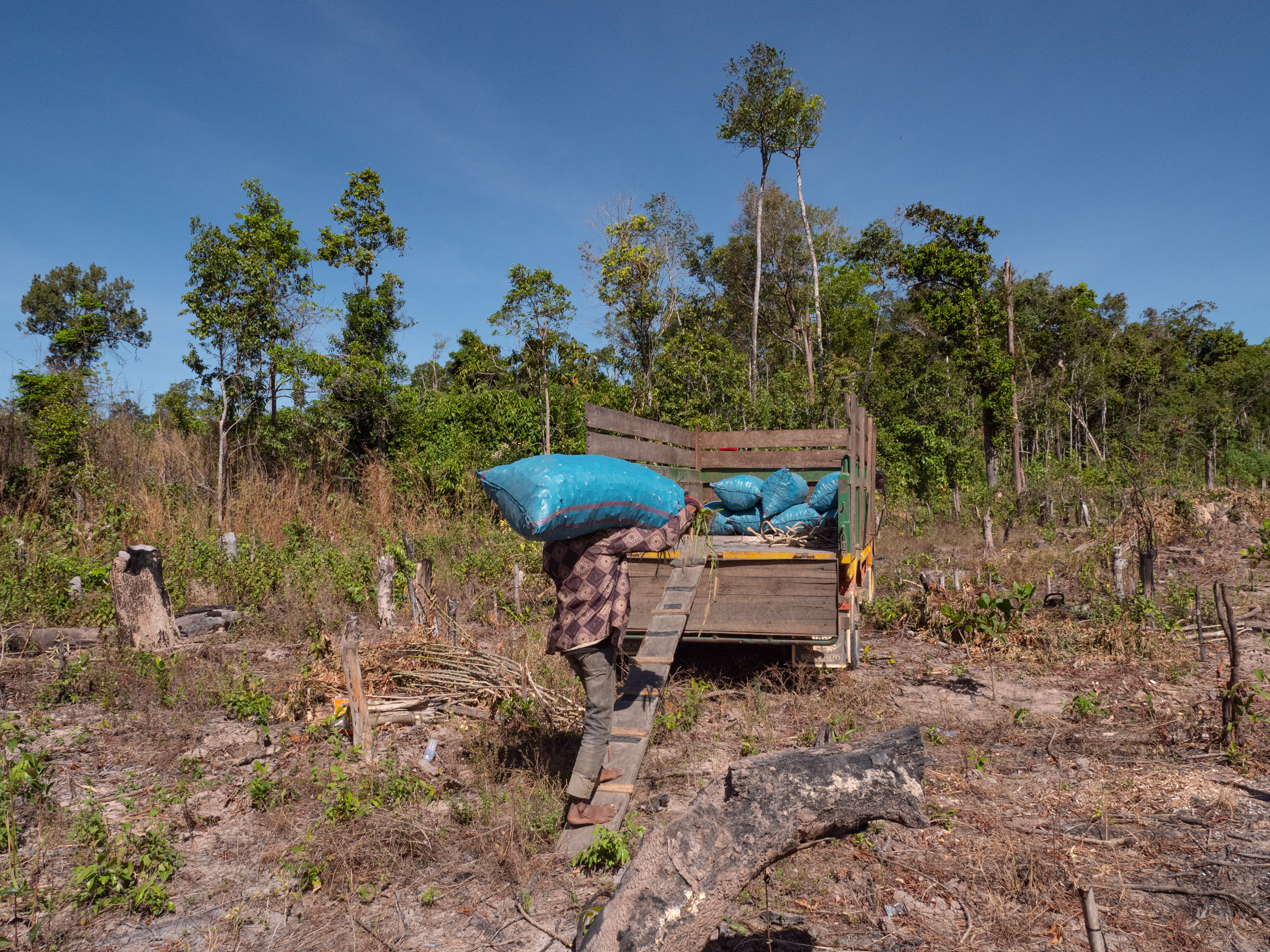 man loading blue sack onto small truck