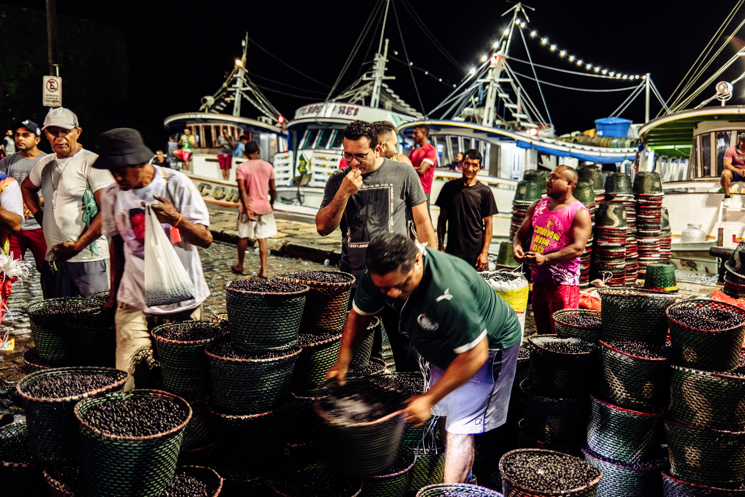 people gathered around large baskets of berries at night