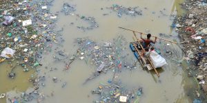 two men on a raft in a plastic waste-filled canal