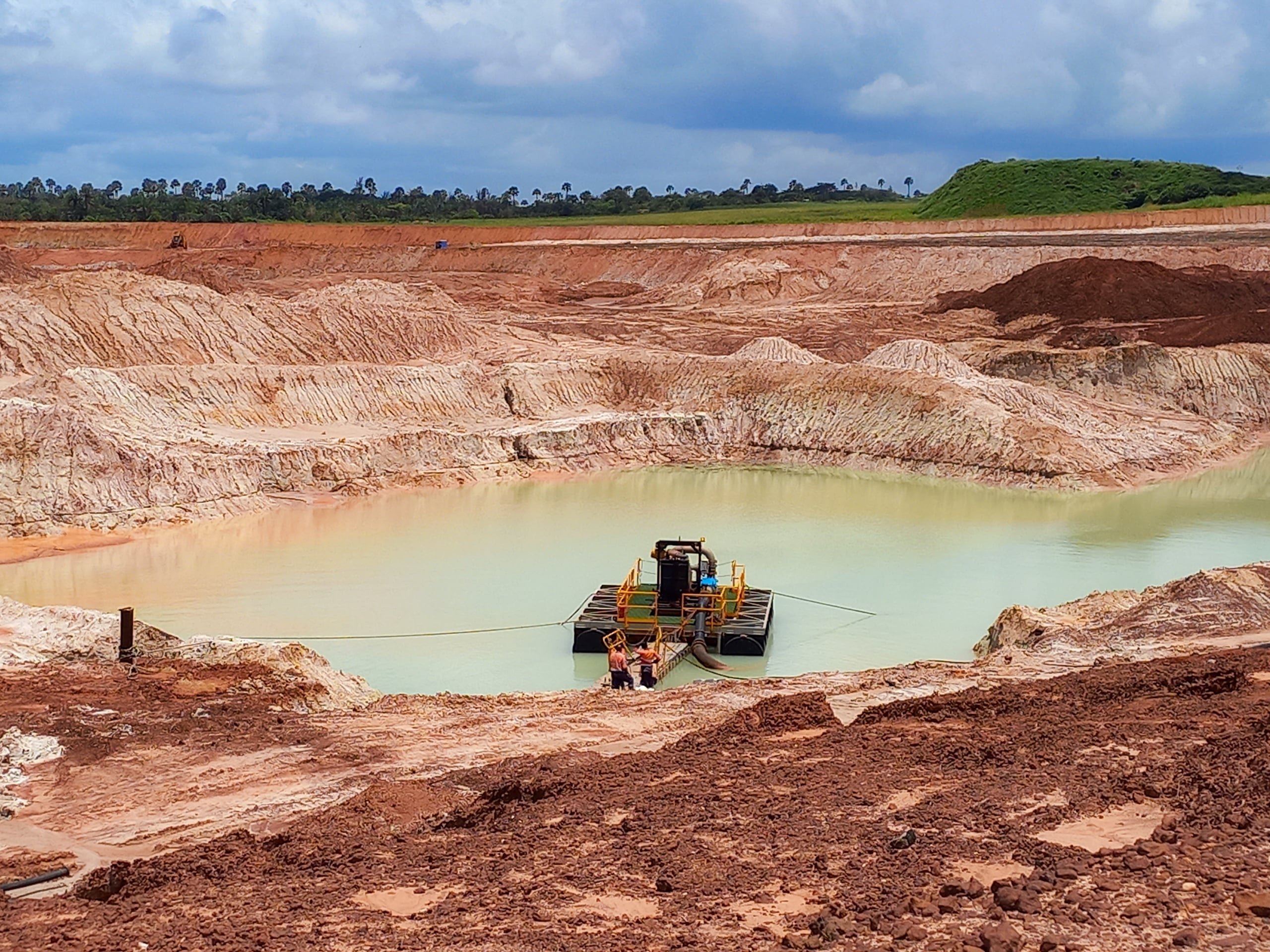 People on platform in the midst of pool of water in open mining site