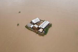 Aerial view of house surrounded by flood water.