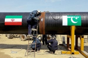workers welds a pipeline with iran and pakistan flags painted on it