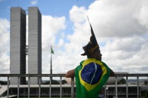man with Brazil flag around shoulders looking out to distance in cityscape