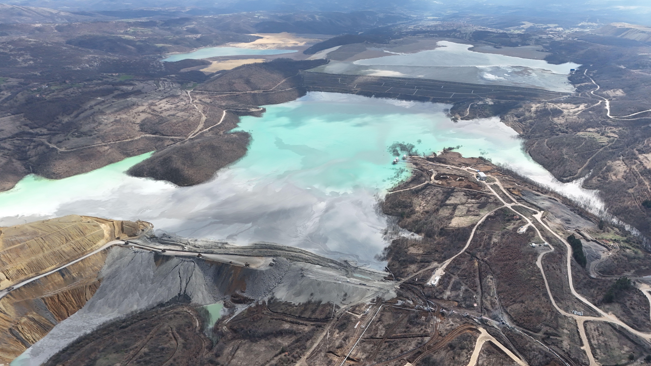 An aerial view of a vast open pit mine, showcasing the massive scale of excavation and mining operations