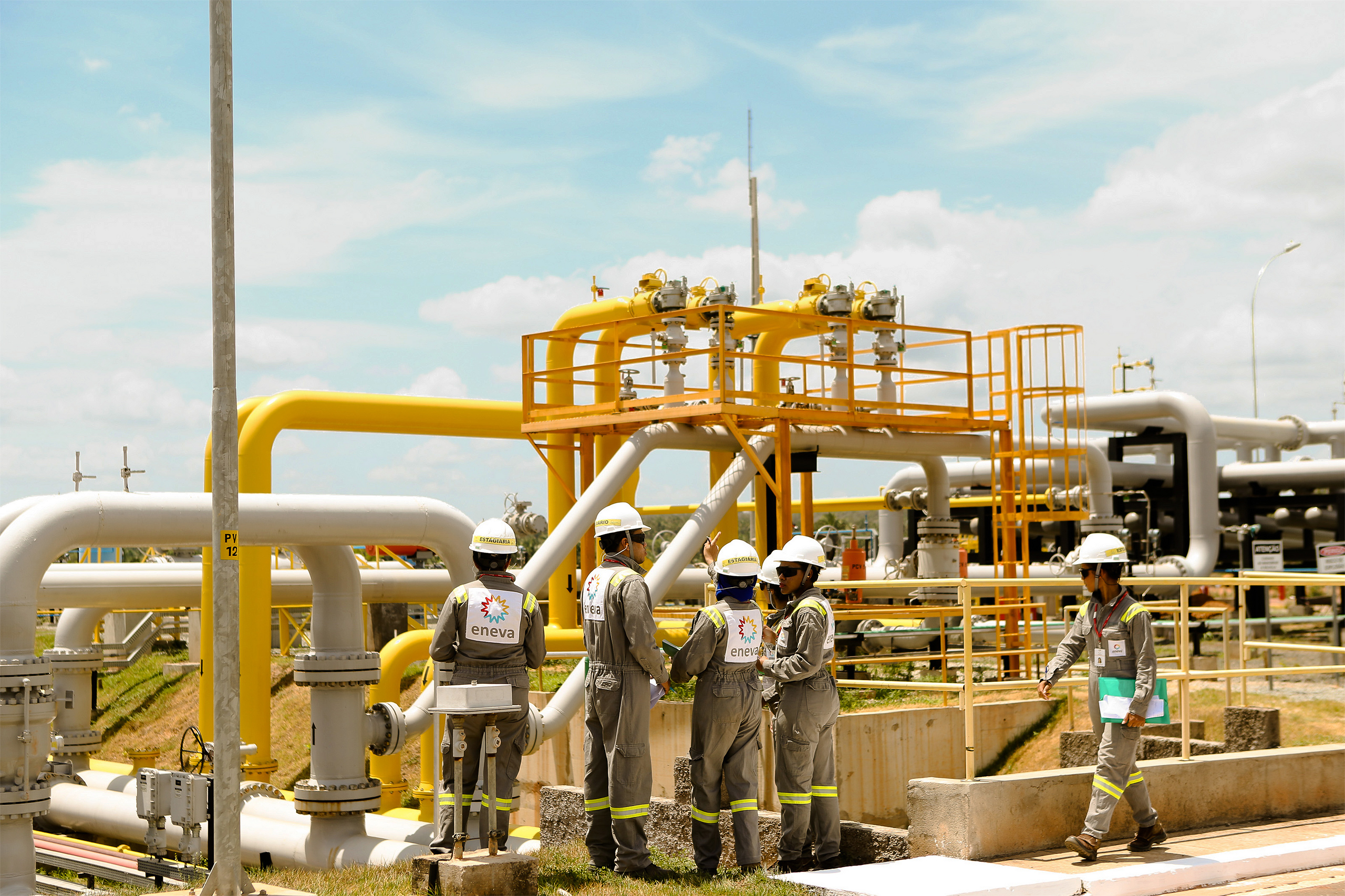 people in hard hats standing near large gas pipes