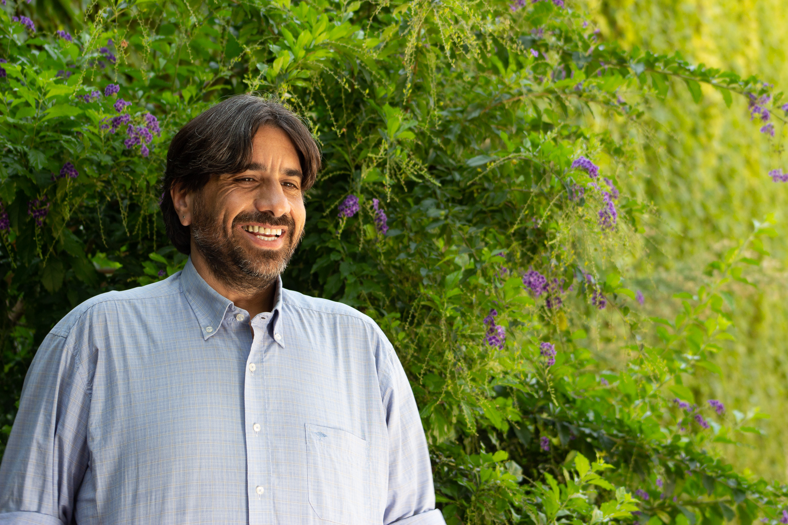 smiling man standing in front of flowering bush