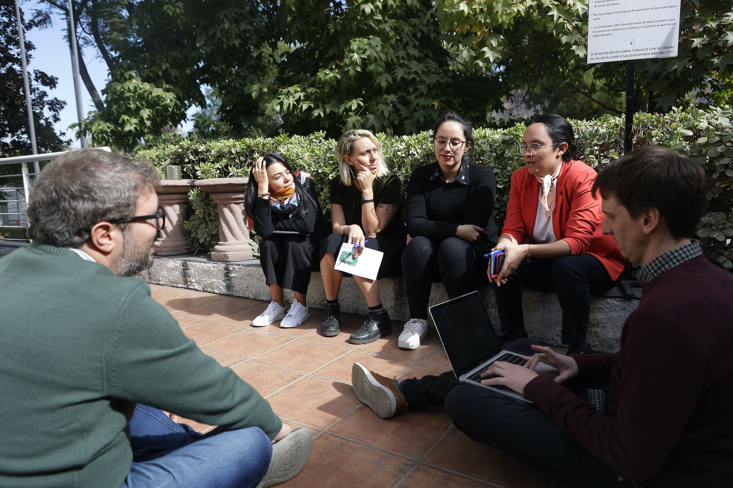 A diverse group of individuals sitting on the ground engaged in conversation