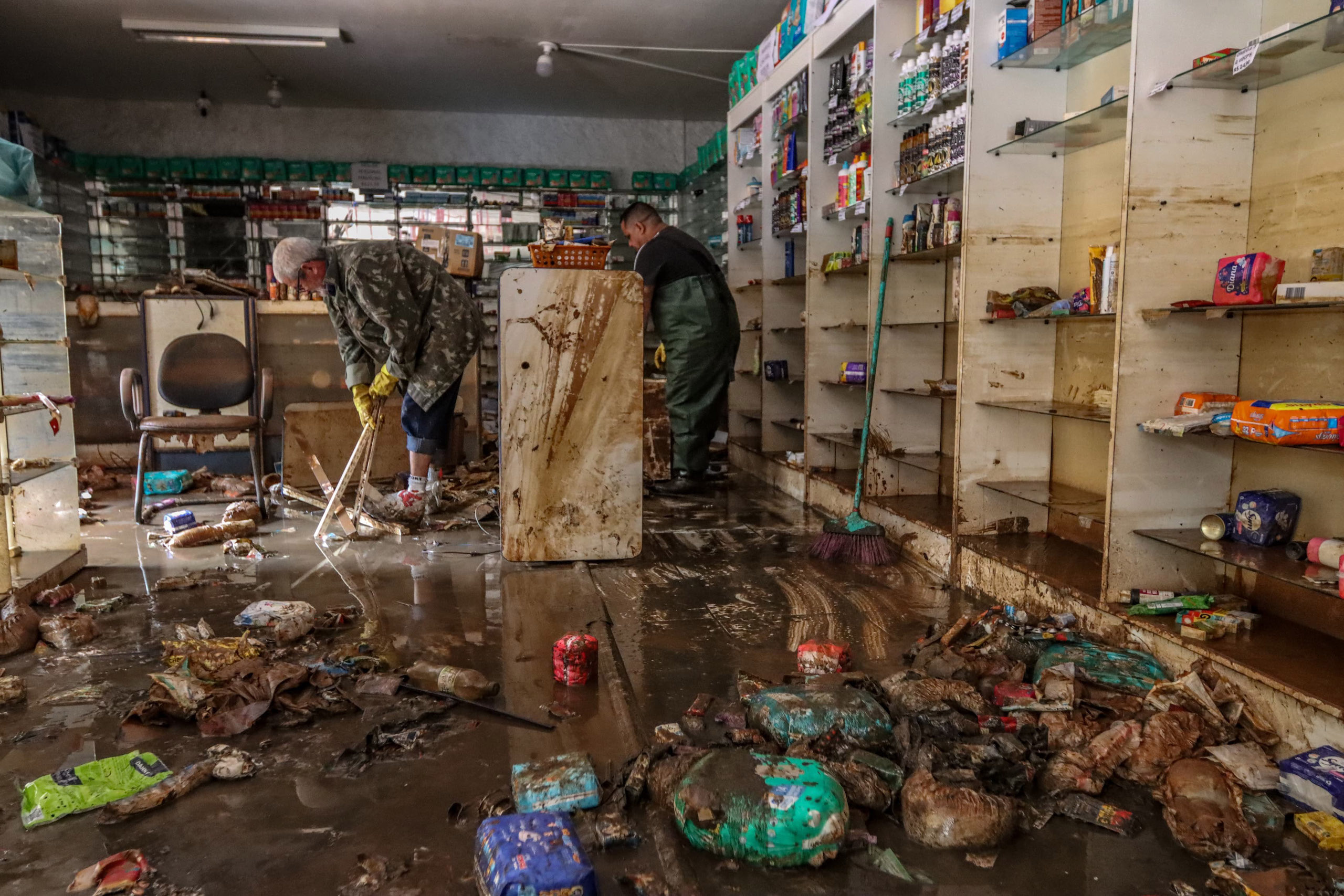 dos personas limpiando un almacén lleno de escombros y basura