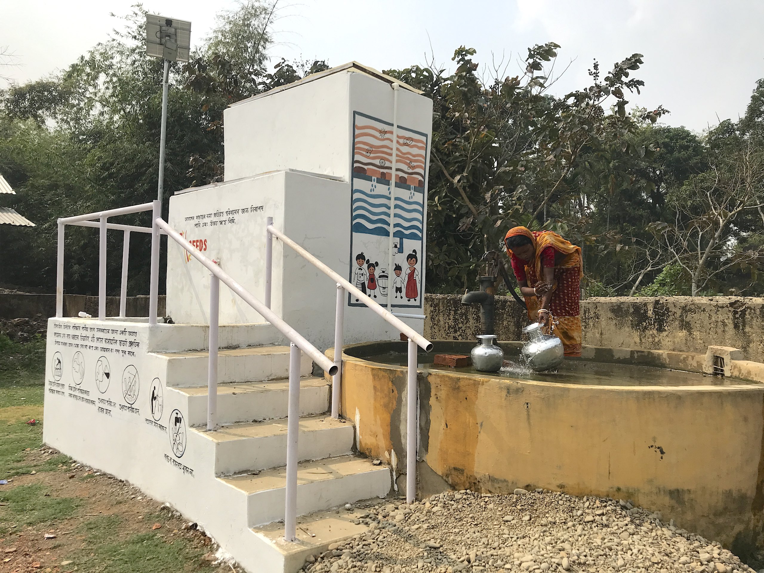 A woman filling water from a well in a rural village