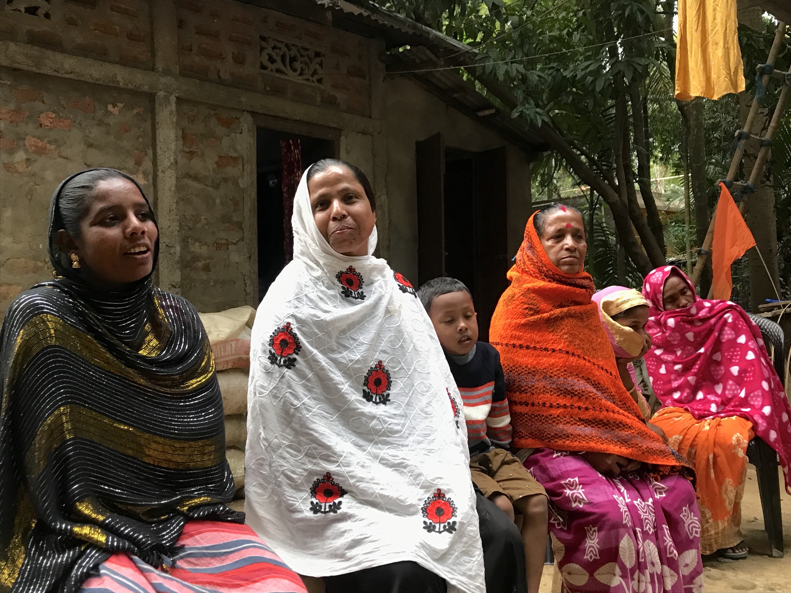 Women in saris sitting outside, engaged in conversation