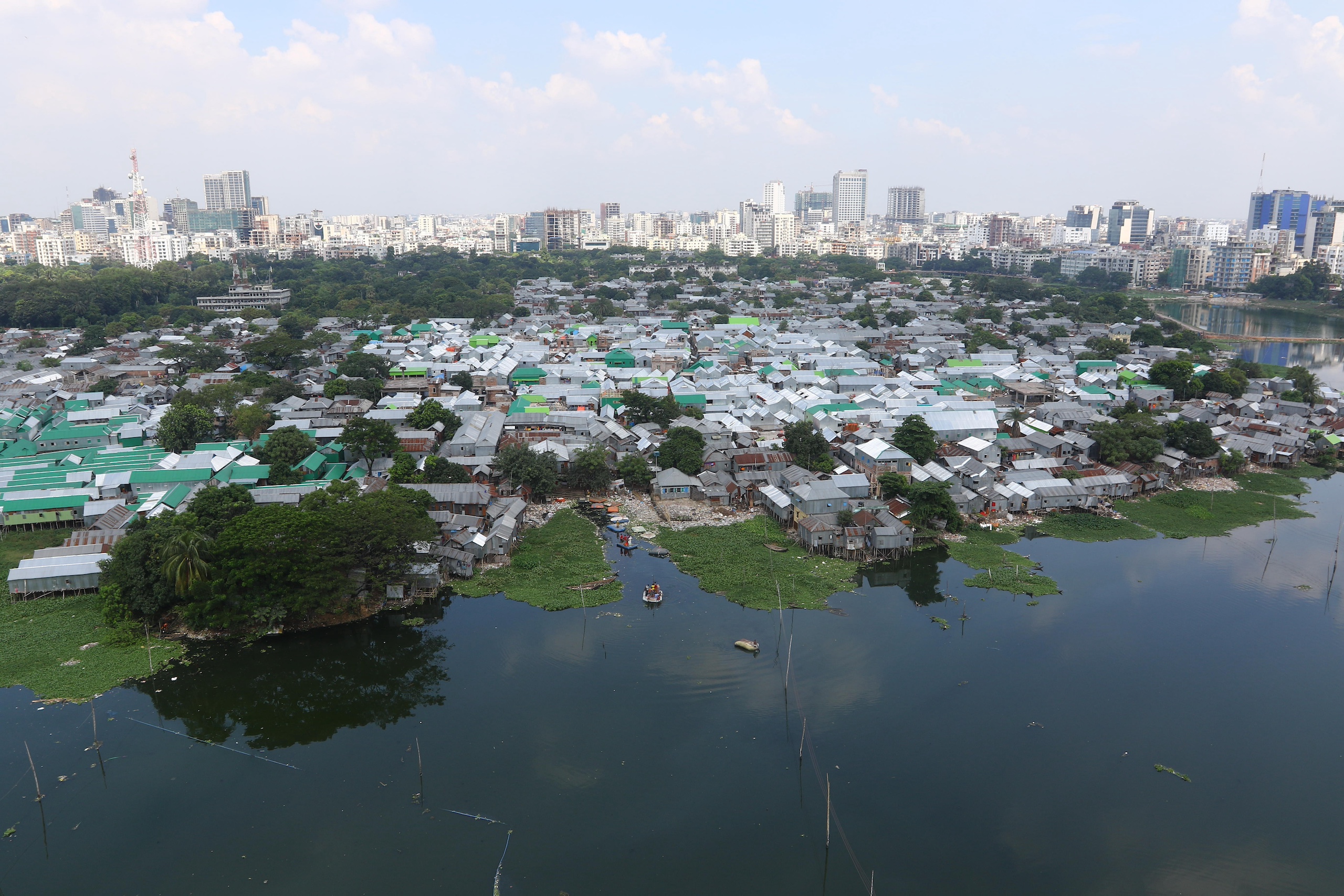 Aerial photograph of a slum on the edge of a river, skyscrapers in the distance
