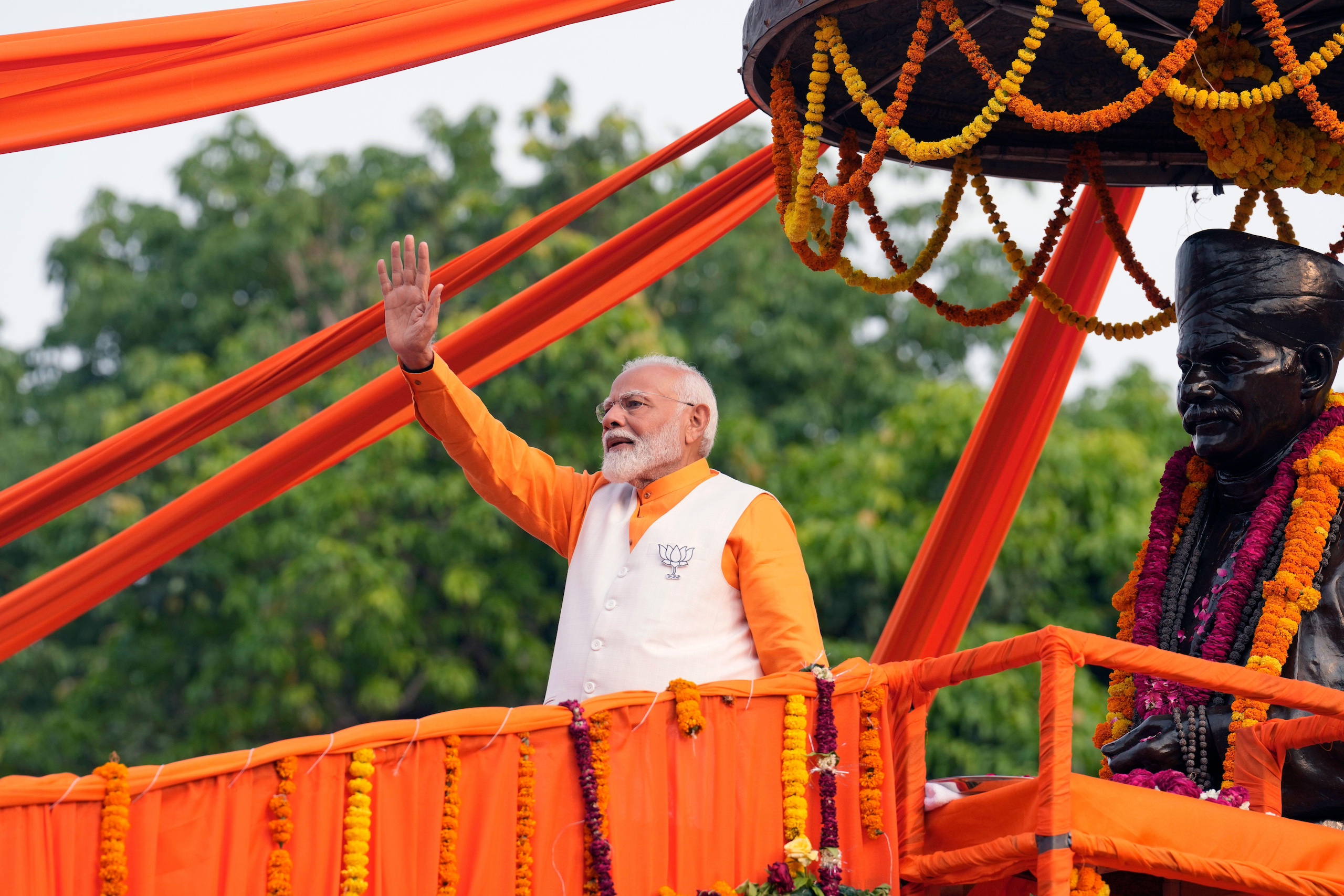 Indian politician Narendra Modi, dressed in orange, waves at a crowd