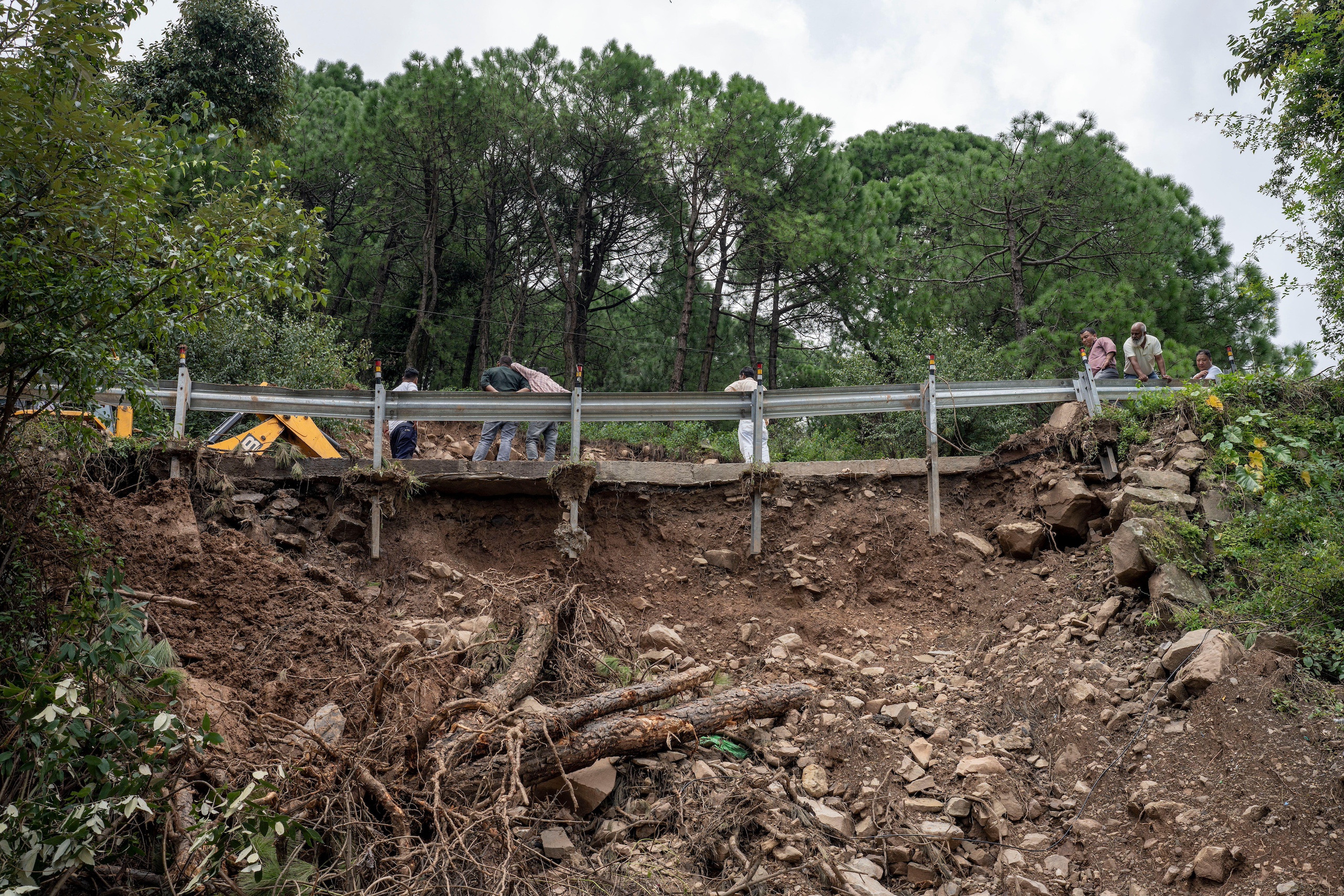 View of rubble and loose soil below a road barrier in a forest
