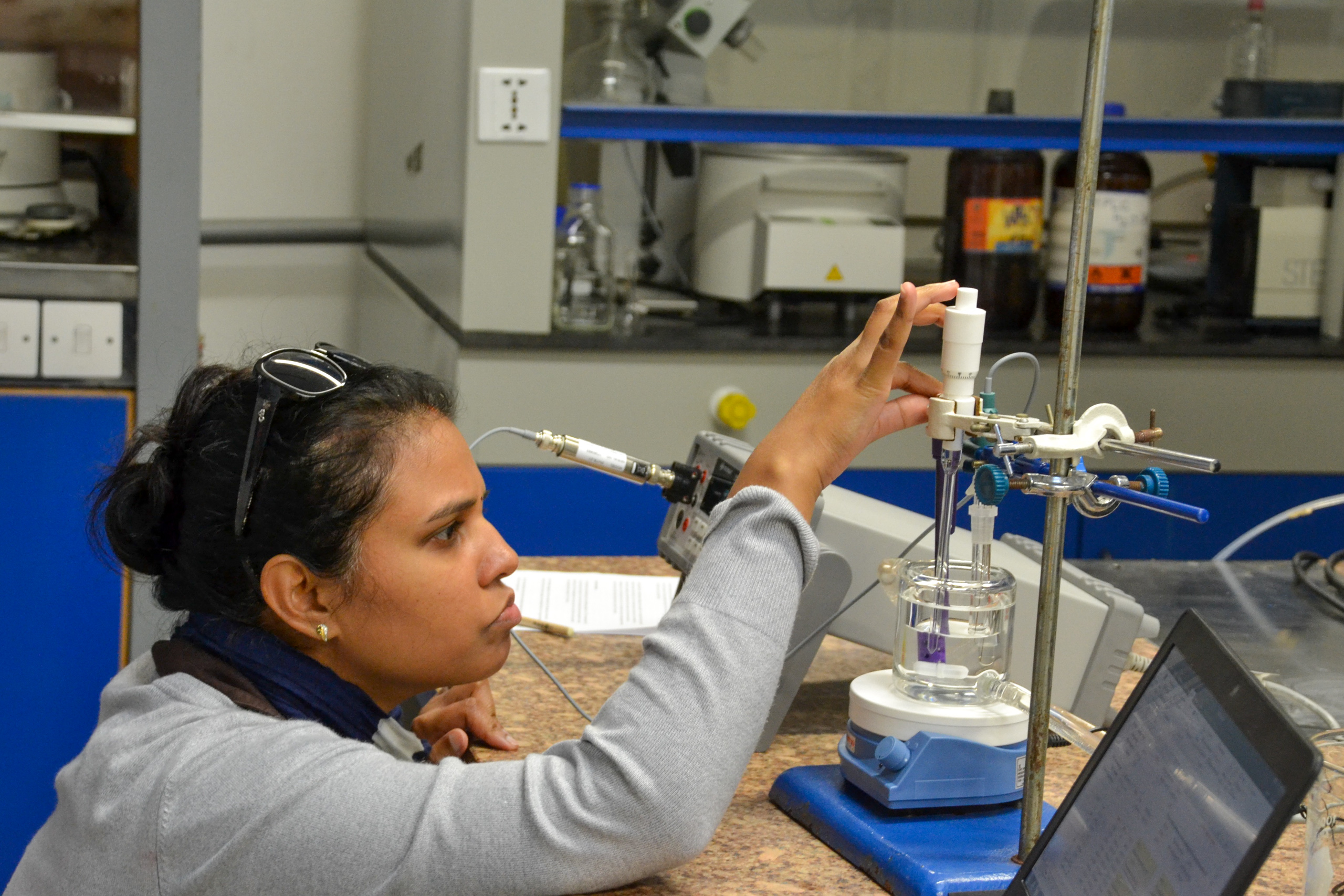 Woman crouching to look at scientific equipment on a table
