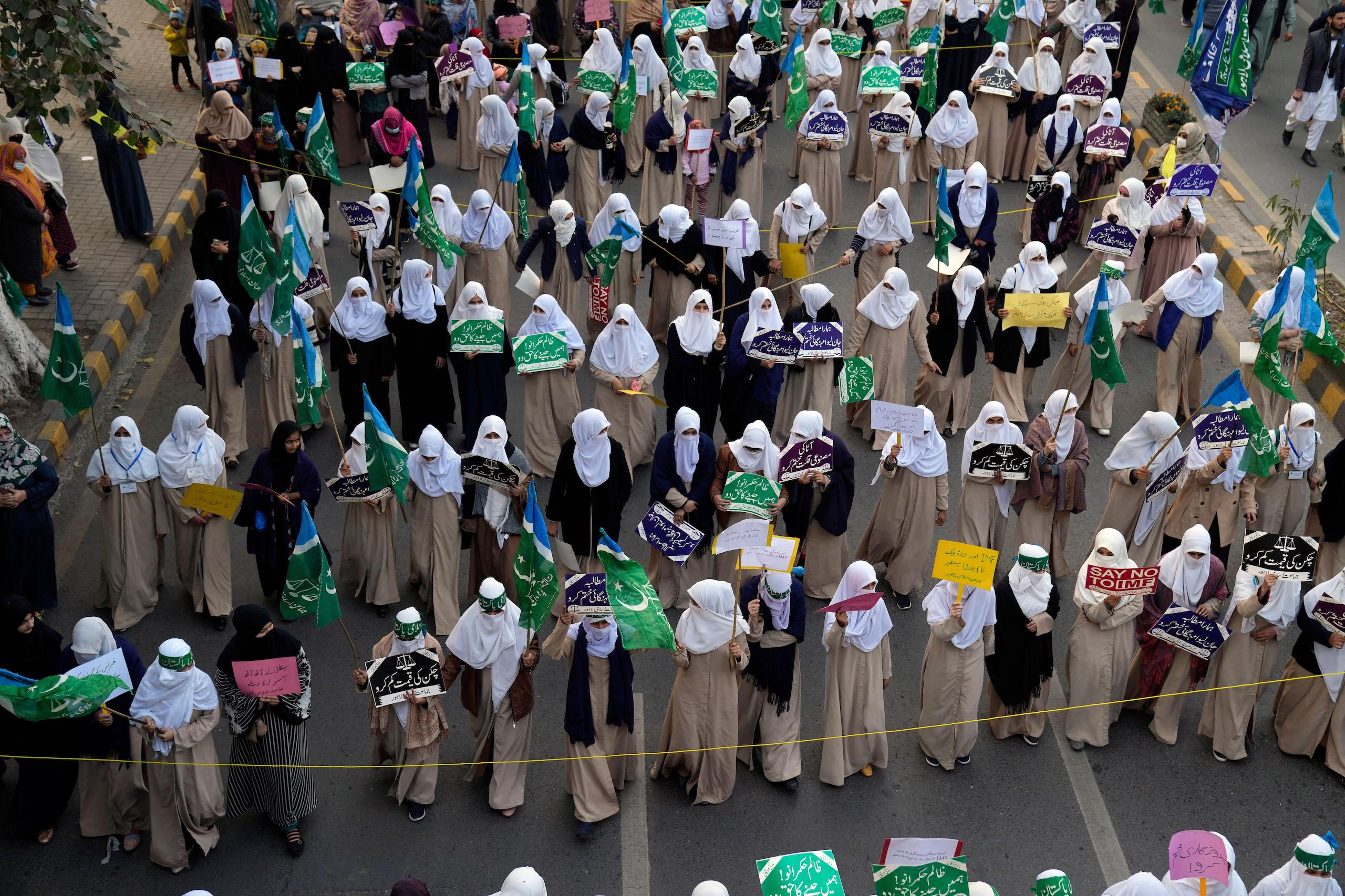 Group of women wearing headscarves, walking on the street and holding signs for a rally