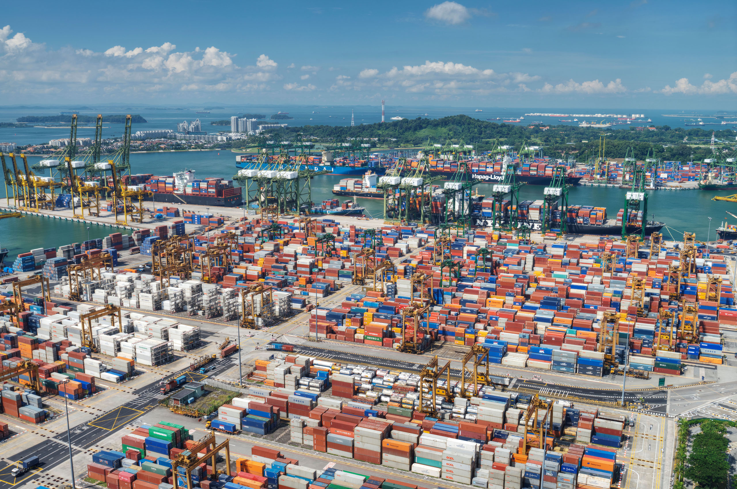 Aerial view of a port filled with colorful shipping containers, cranes, and docked cargo ships