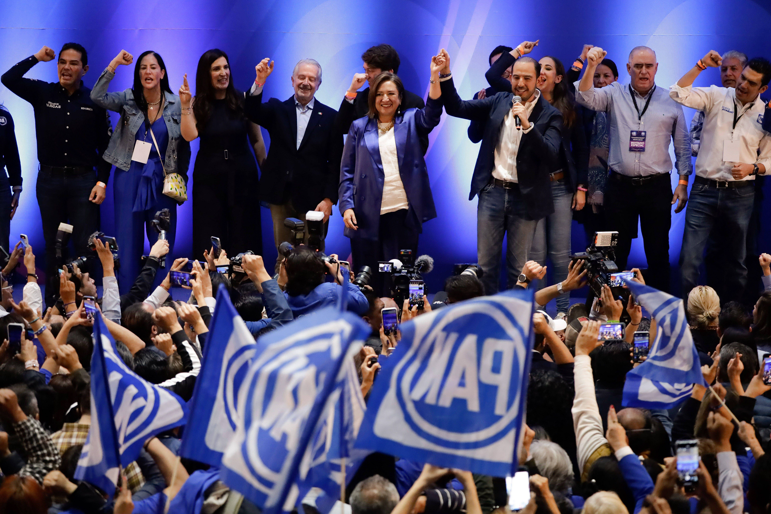 Xochitl Galvez surrounded by people on stage in front oof crowd of photographers