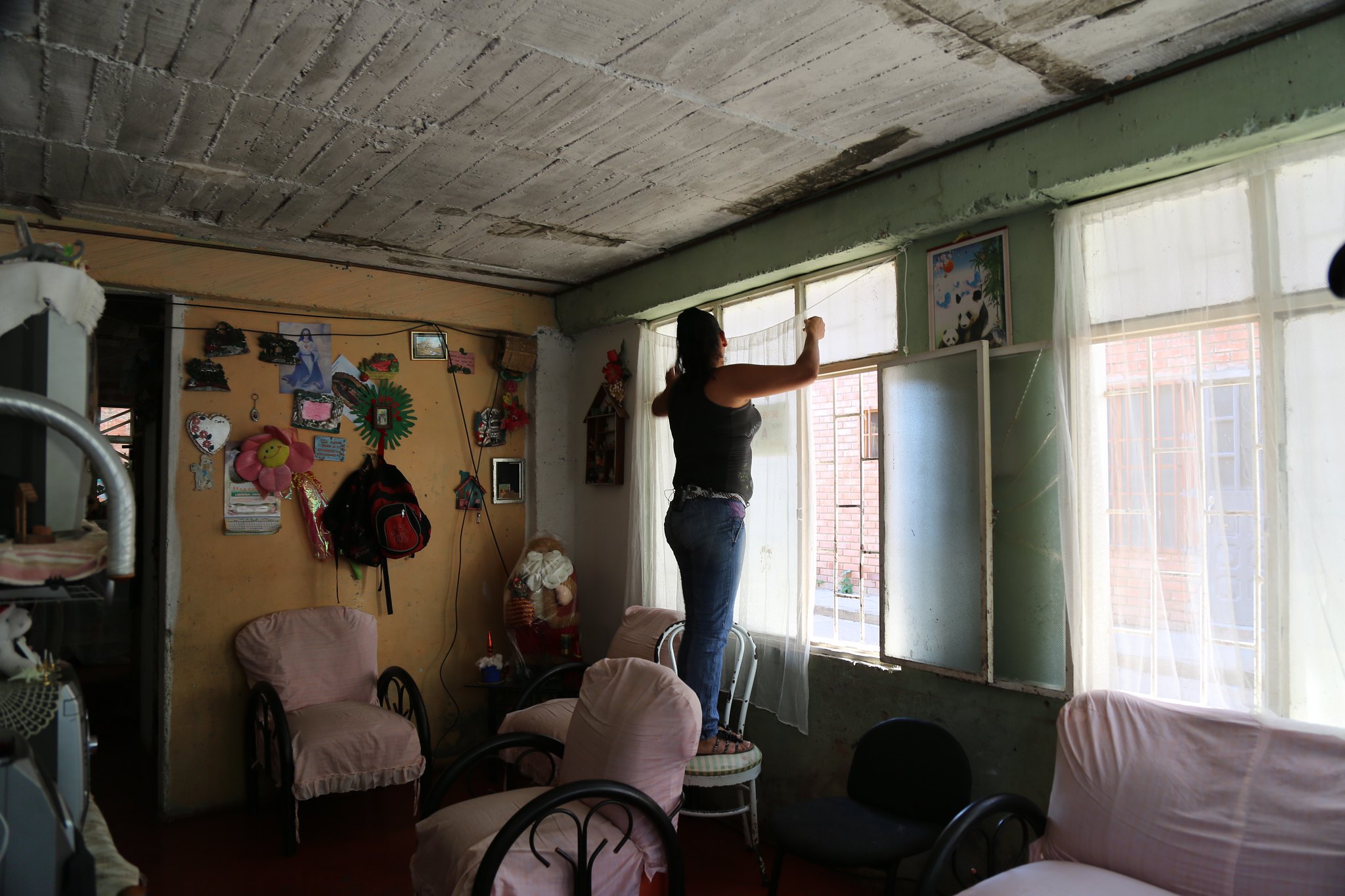 woman on chair placing fine netting over window