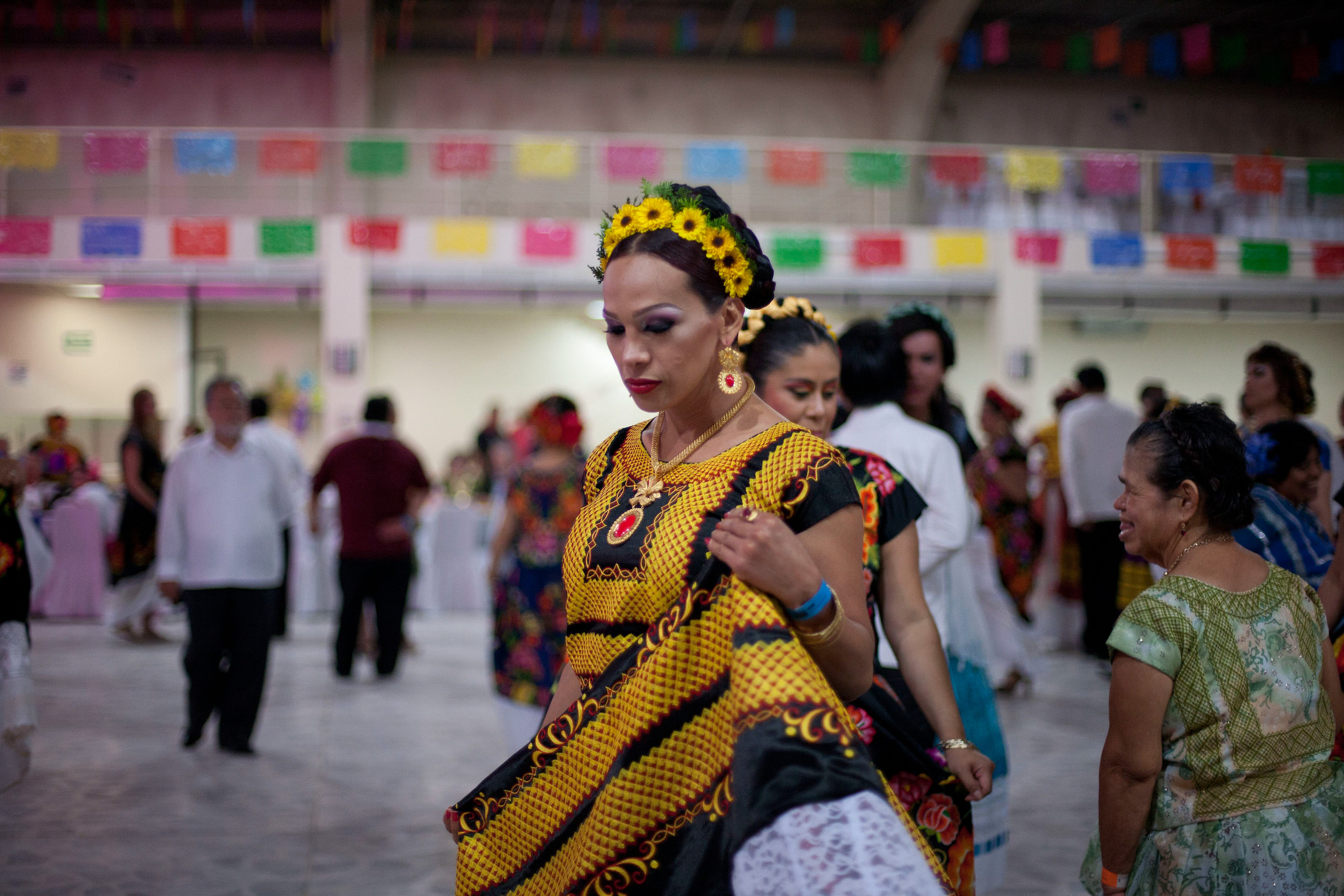 Una persona con un vestido amarillo y negro camina entre otras personas