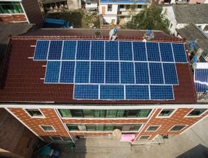 Aerial view of workers installing solar panels on the roof of a residential building
