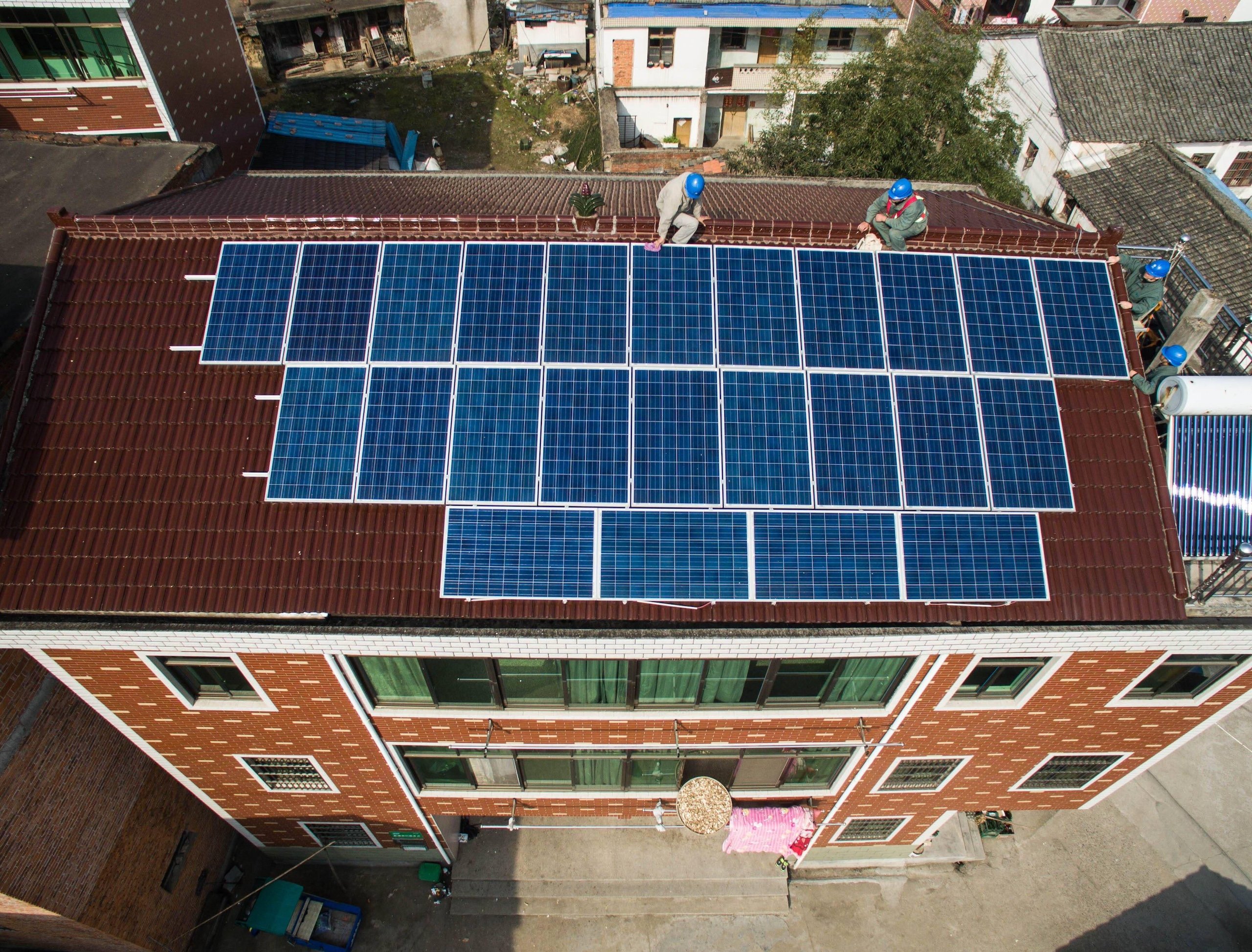 <p>Technicians test solar panels on a residential building in Yiwu, east China&#8217;s Zhejiang province. In Hubei province&#8217;s Wuhan, residents of Beihu have assigned their rooftop solar rights to a power firm. In return, they get a large discount on their service charge and improvements to their communal rooftop space (Image: Alamy)</p>