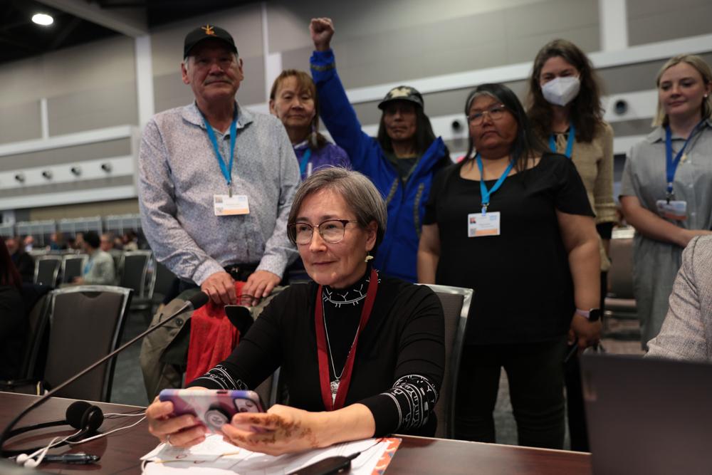 group of people standing behind seated Lisa Koperqualuk