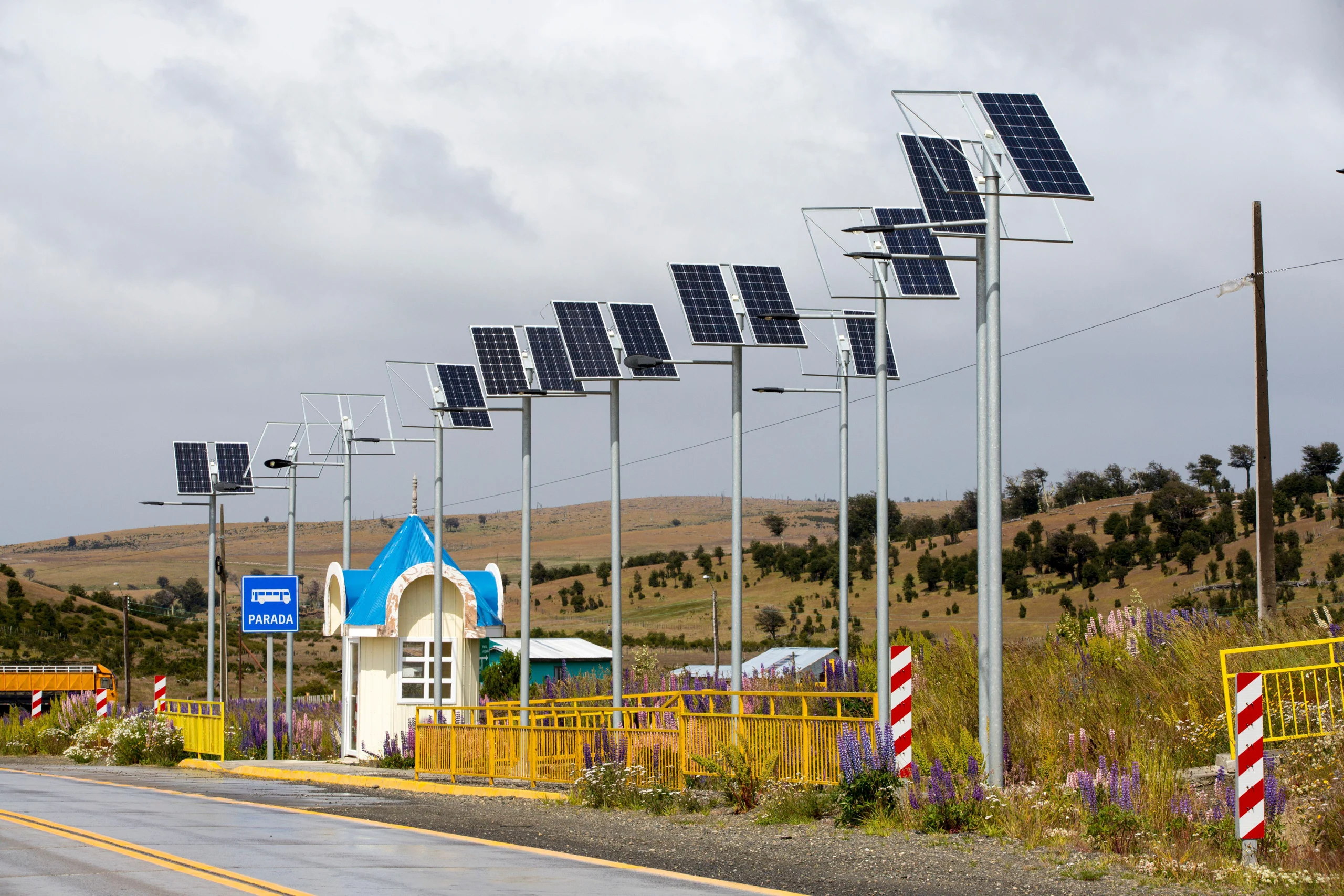 fila de postes de luz con paneles solares a lo largo de una carretera