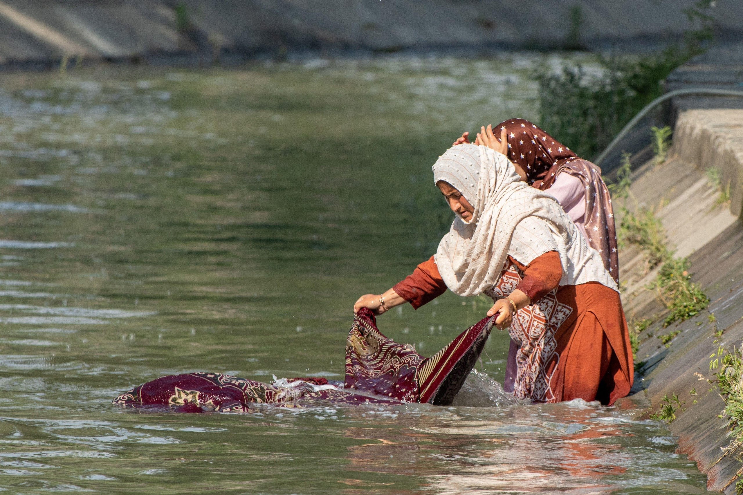 <p><span style="font-weight: 400;">जम्मू एवं कश्मीर की ग्रीष्मकालीन राजधानी श्रीनगर में एक नहर में कंबल धोती कश्मीरी महिलाएं (फोटो: अलामी)</span></p>