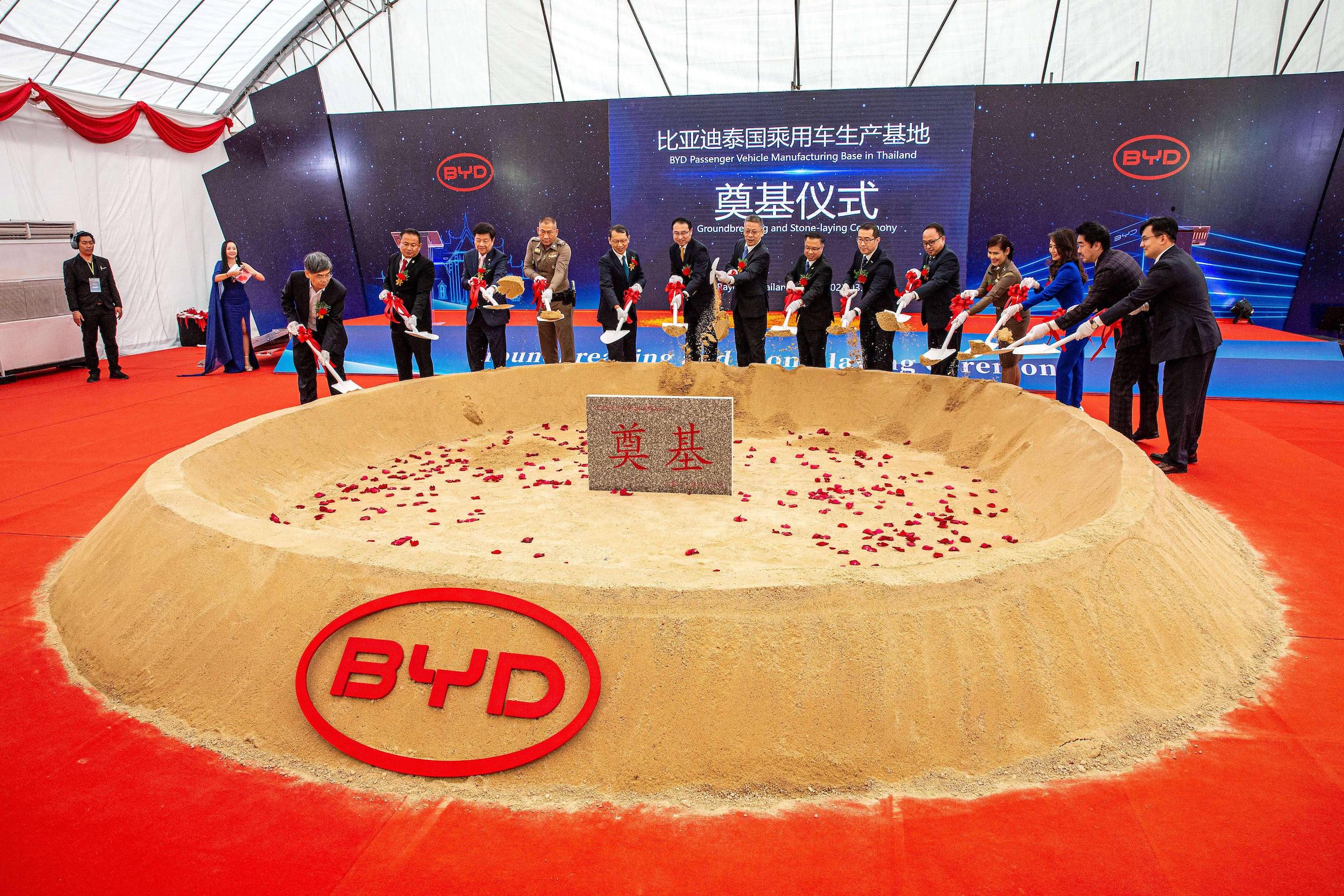 A group of people standing around a large sand pit, engaged in an event