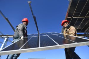workers with safety helmets raising a solar panel