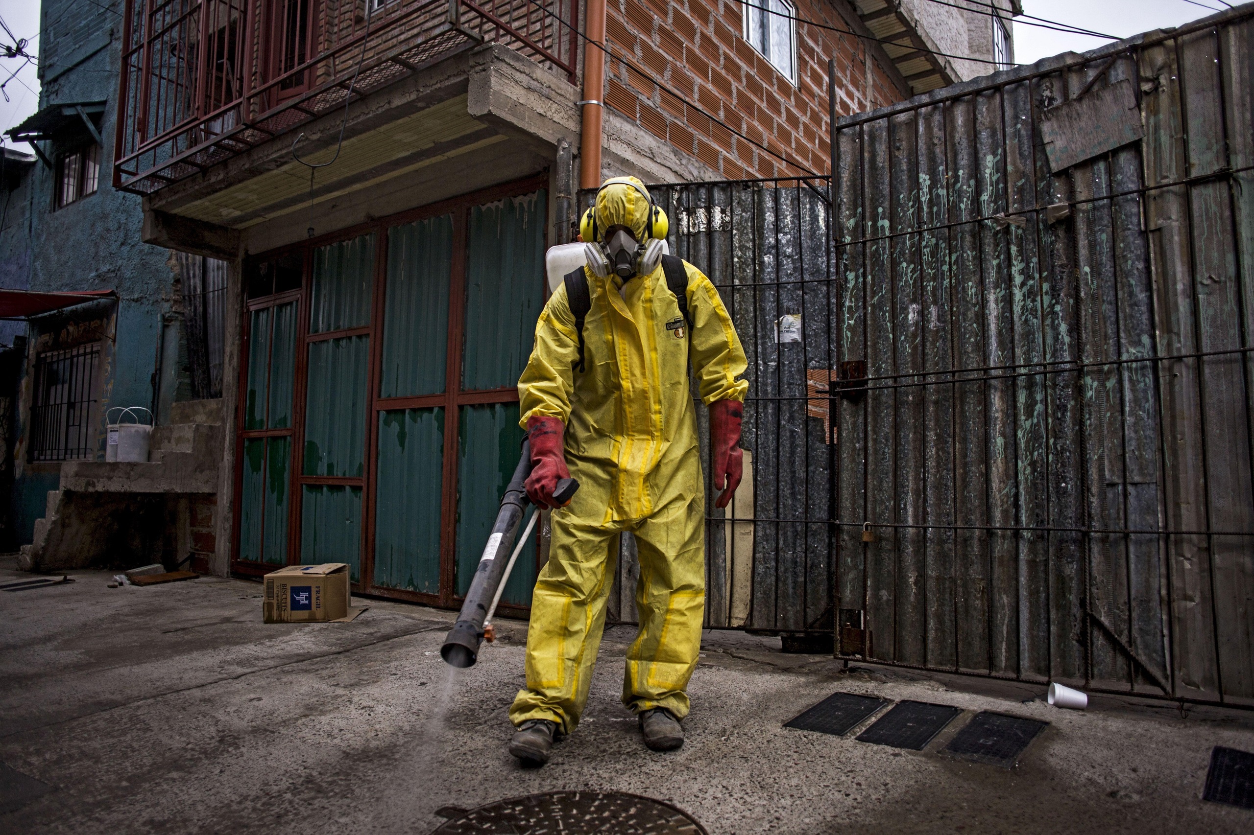 Una persona con un traje de protección amarillo utilizando un fumigador