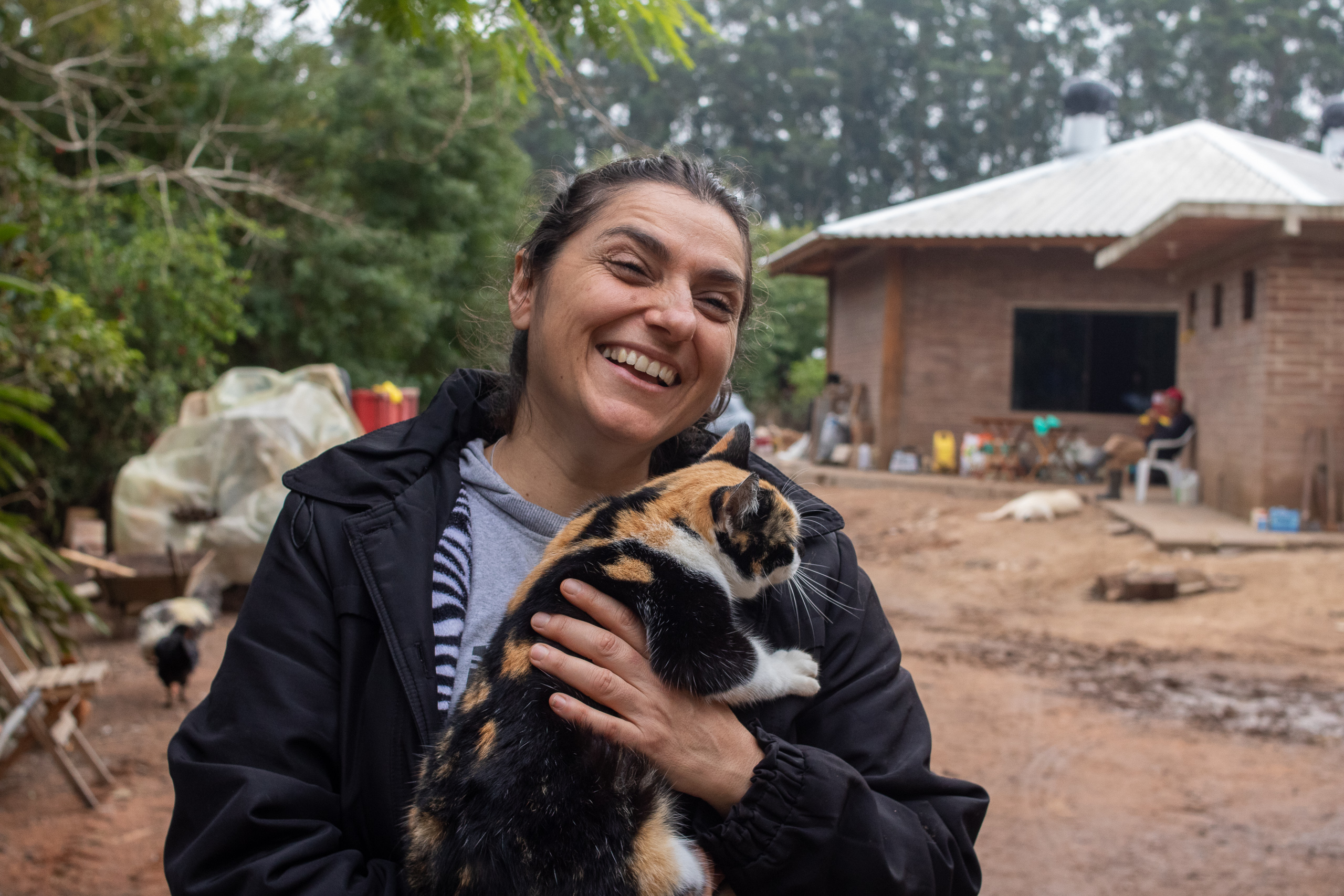 Una mujer sonriendo y sosteniendo a un gato