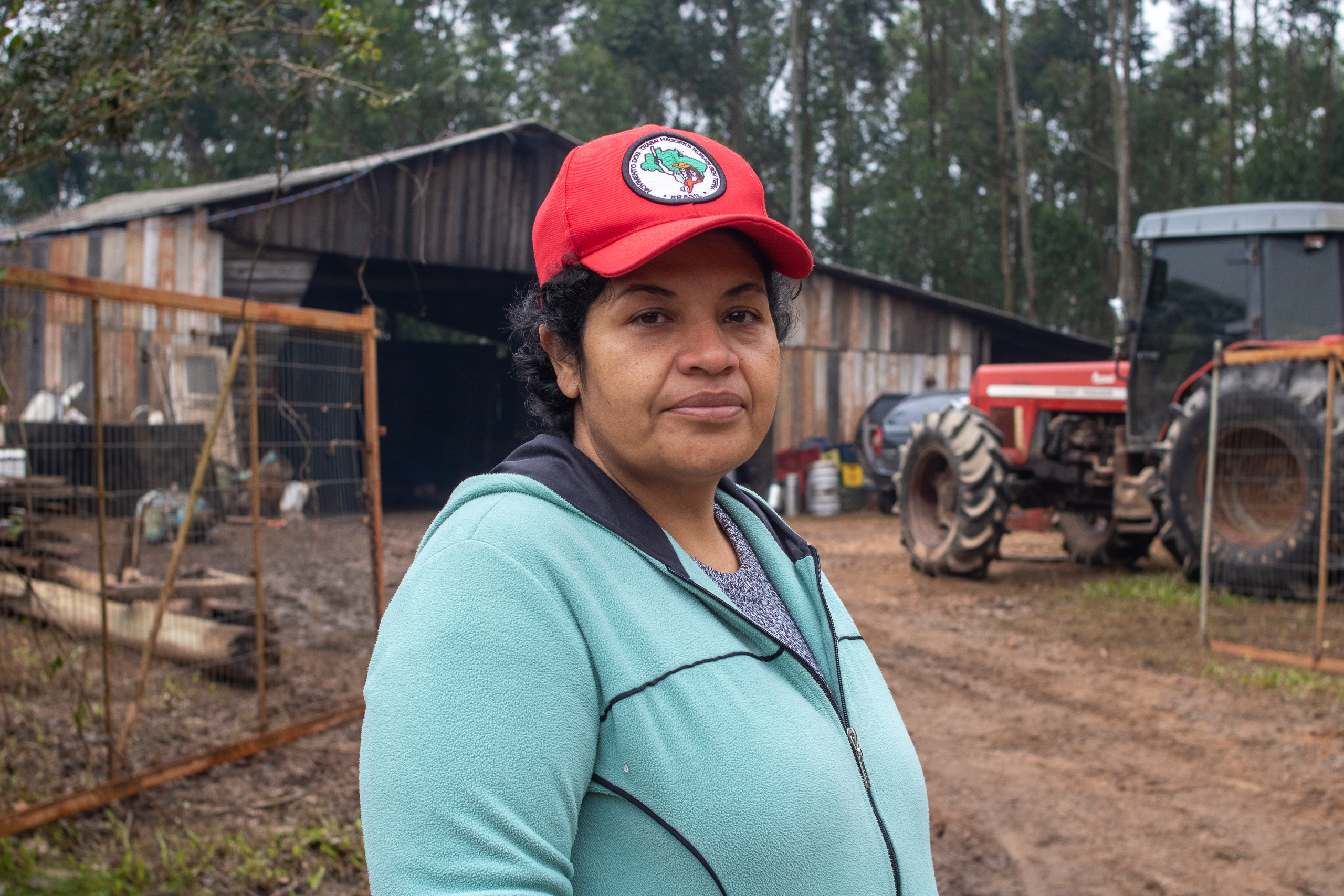 una mujer con una gorra roja, fuera de un granero