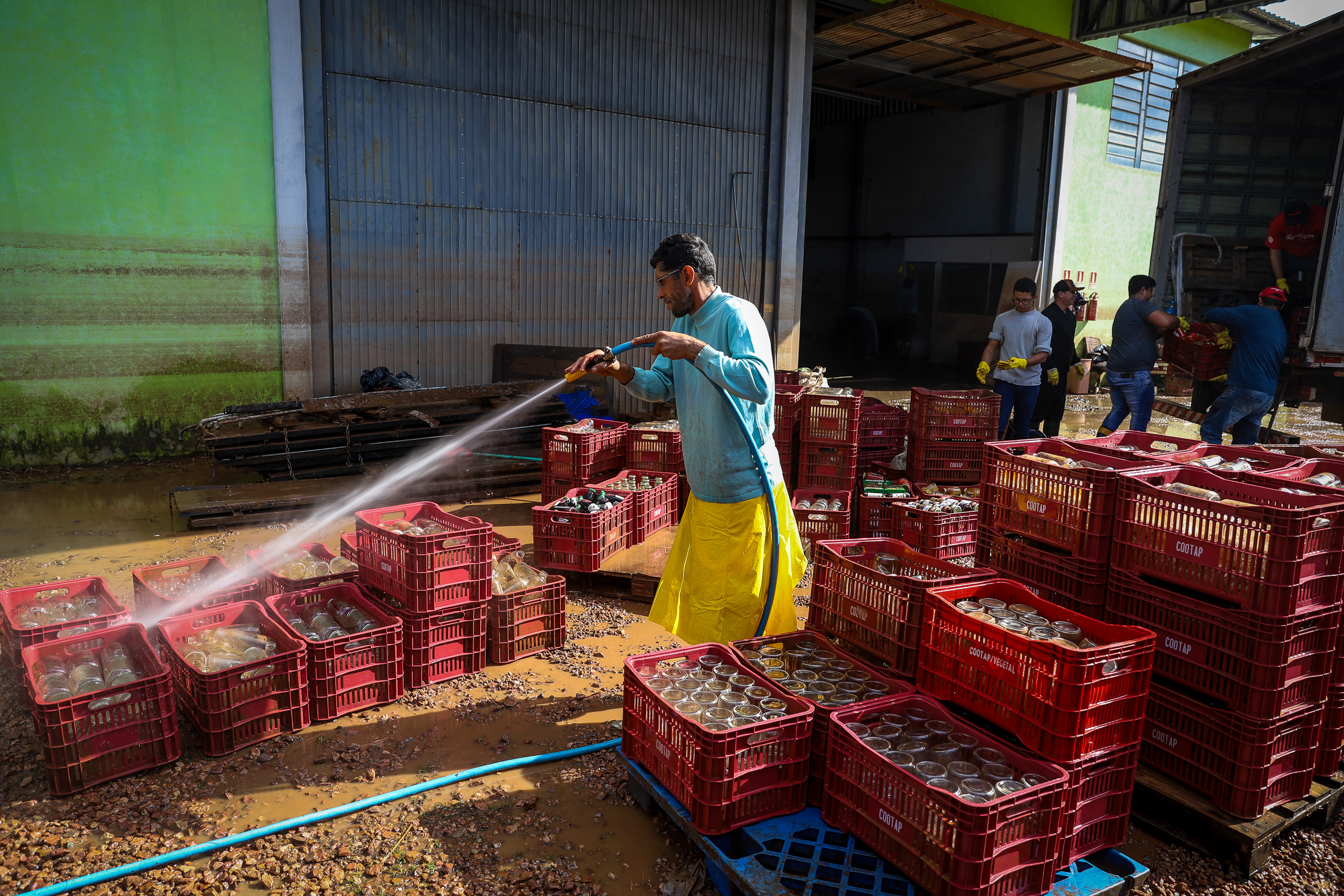 man washing glass containers with hose
