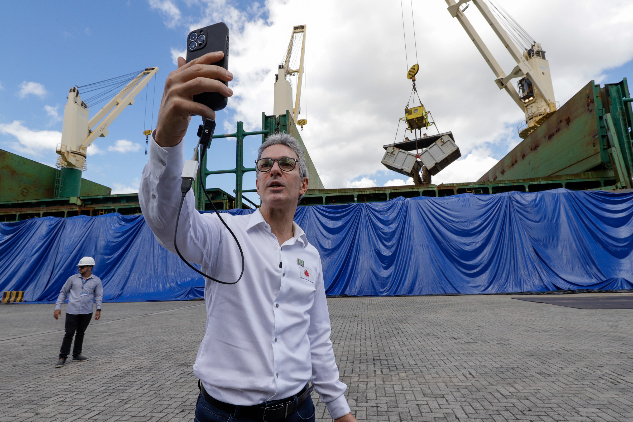 Un hombre con una camisa blanca sacándose una selfie en un puerto