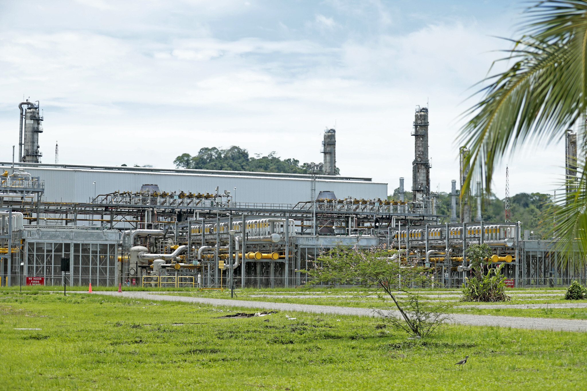 a gas plant with smokestacks emitting steam and surrounded by machinery and pipelines