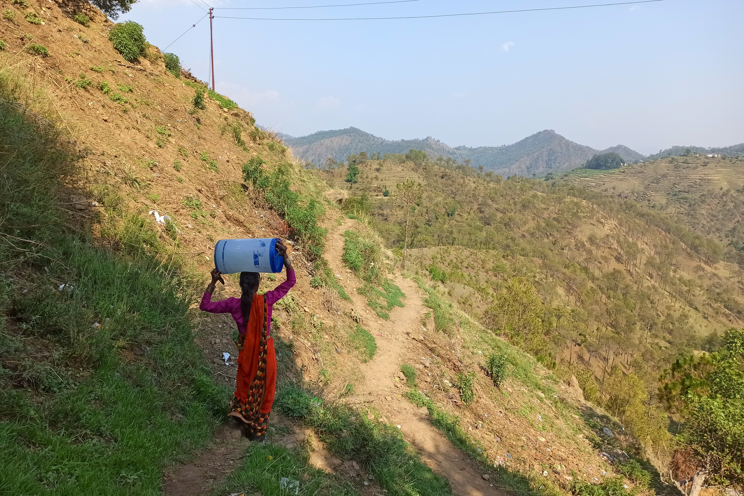 a woman carrying water container on head in rural village