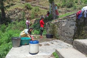 Women washing water from bucket on hillside