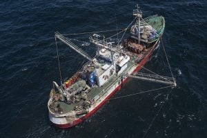 Aerial view of a trawler fishing vessel against a deep blue ocean