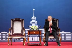 Russian president Vladimir Putin sits in a chair next to an empty chair