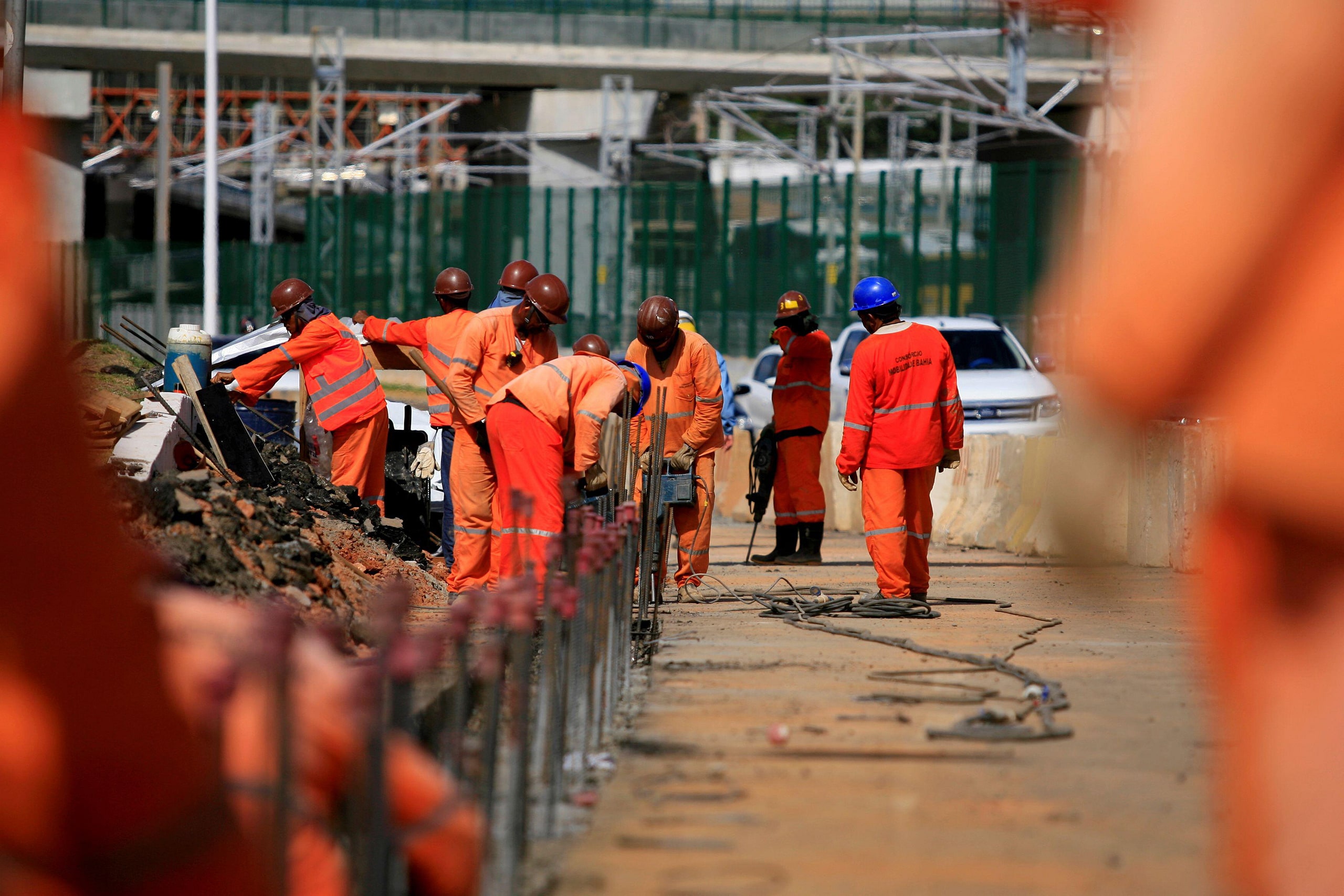 Trabajadores con uniformes anaranjados y cascos en una calle