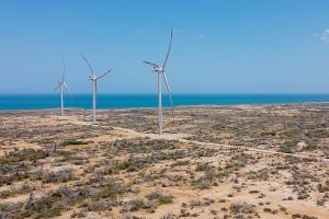 three large wind turbines in barren area near coast