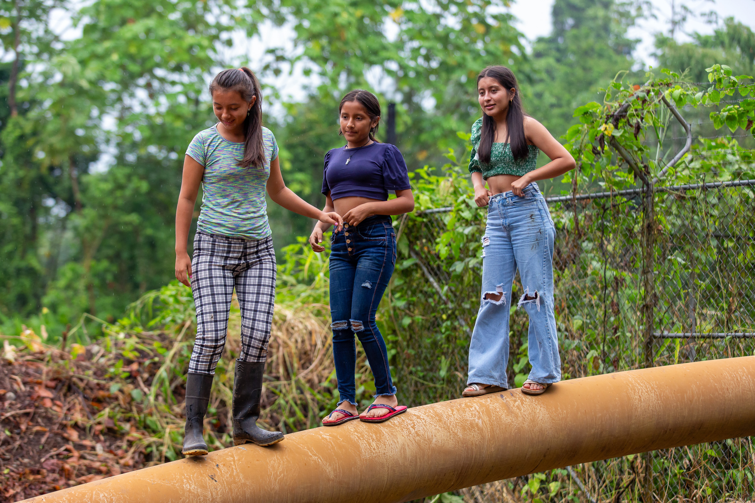 tres chicas jóvenes de pie sobre una tubería