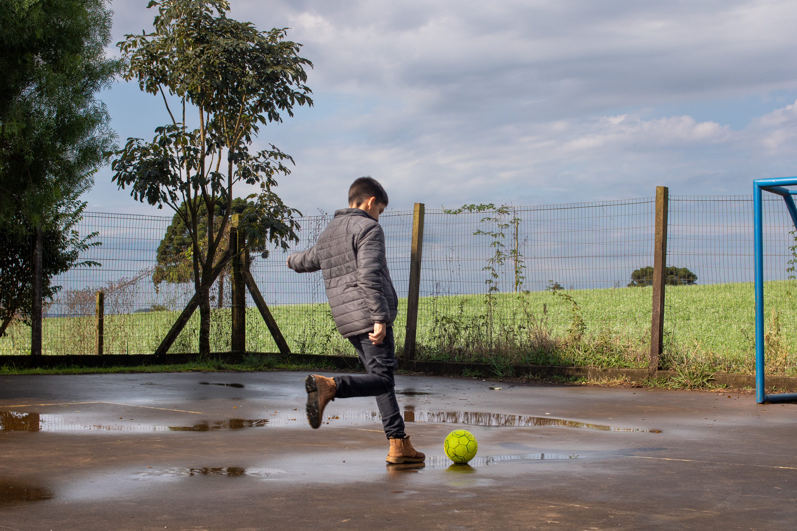 boy kicking ball near puddles