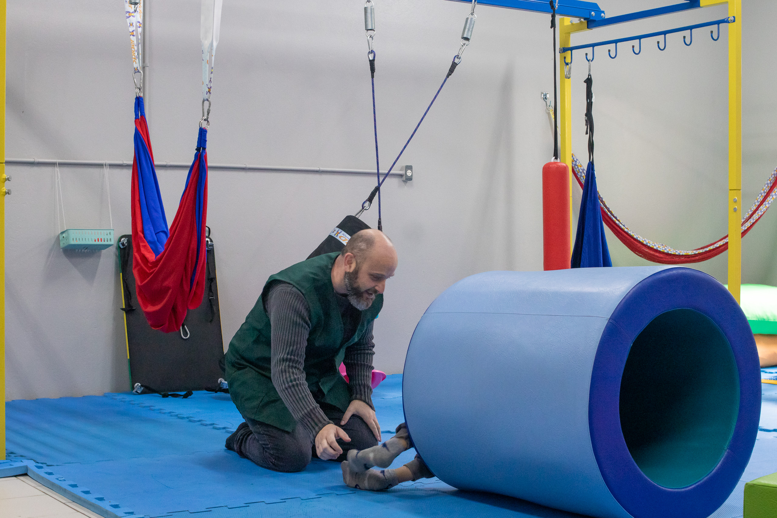 man reaching for child in large blue tube