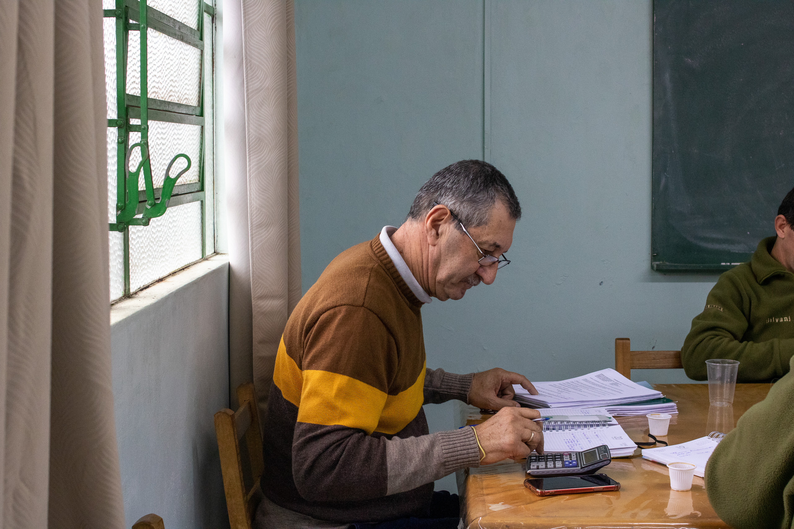 Un hombre hace cuentas con una calculadora y cuadernos a su alrededor