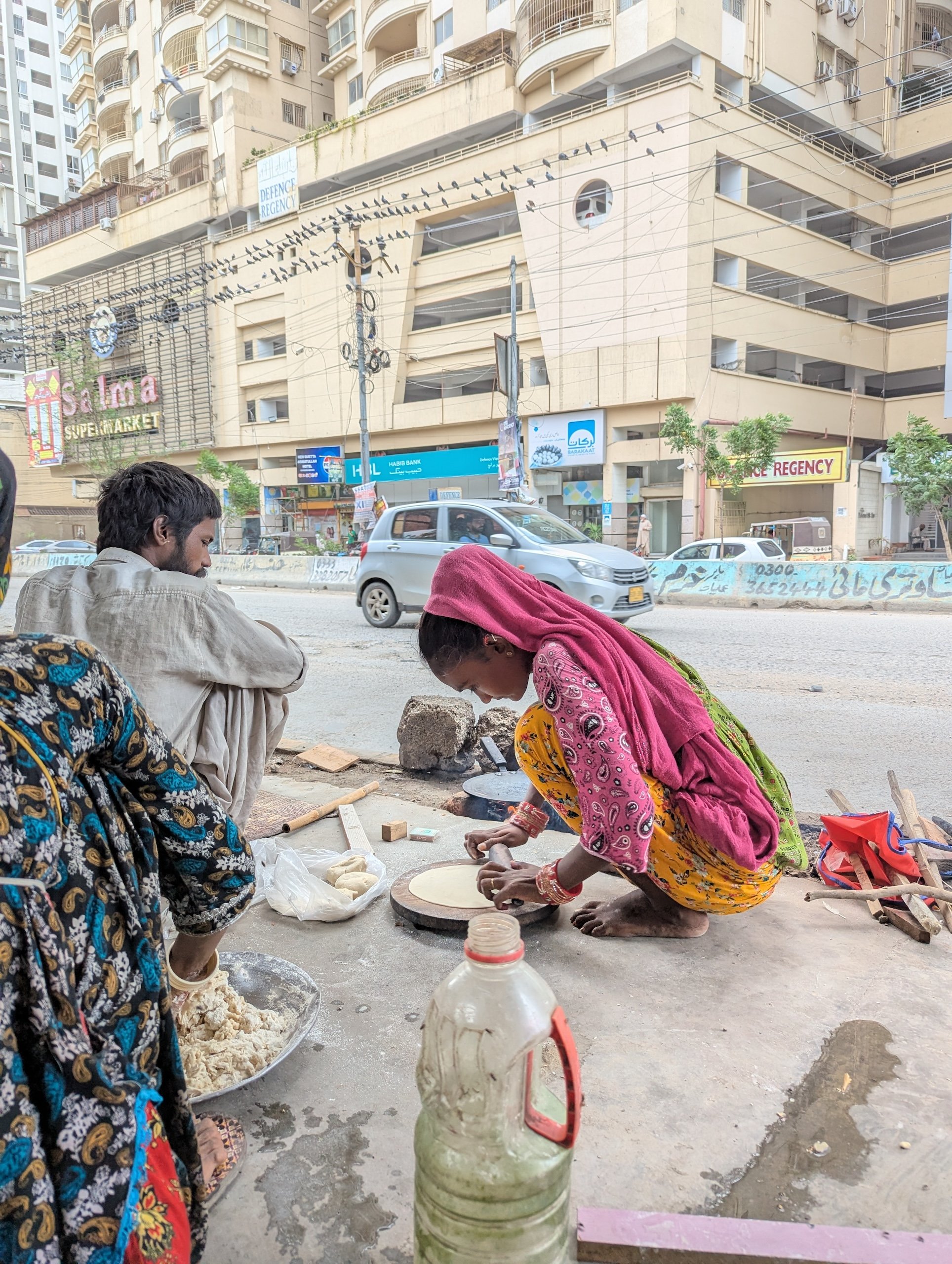 a woman making bread on the street under a flyover