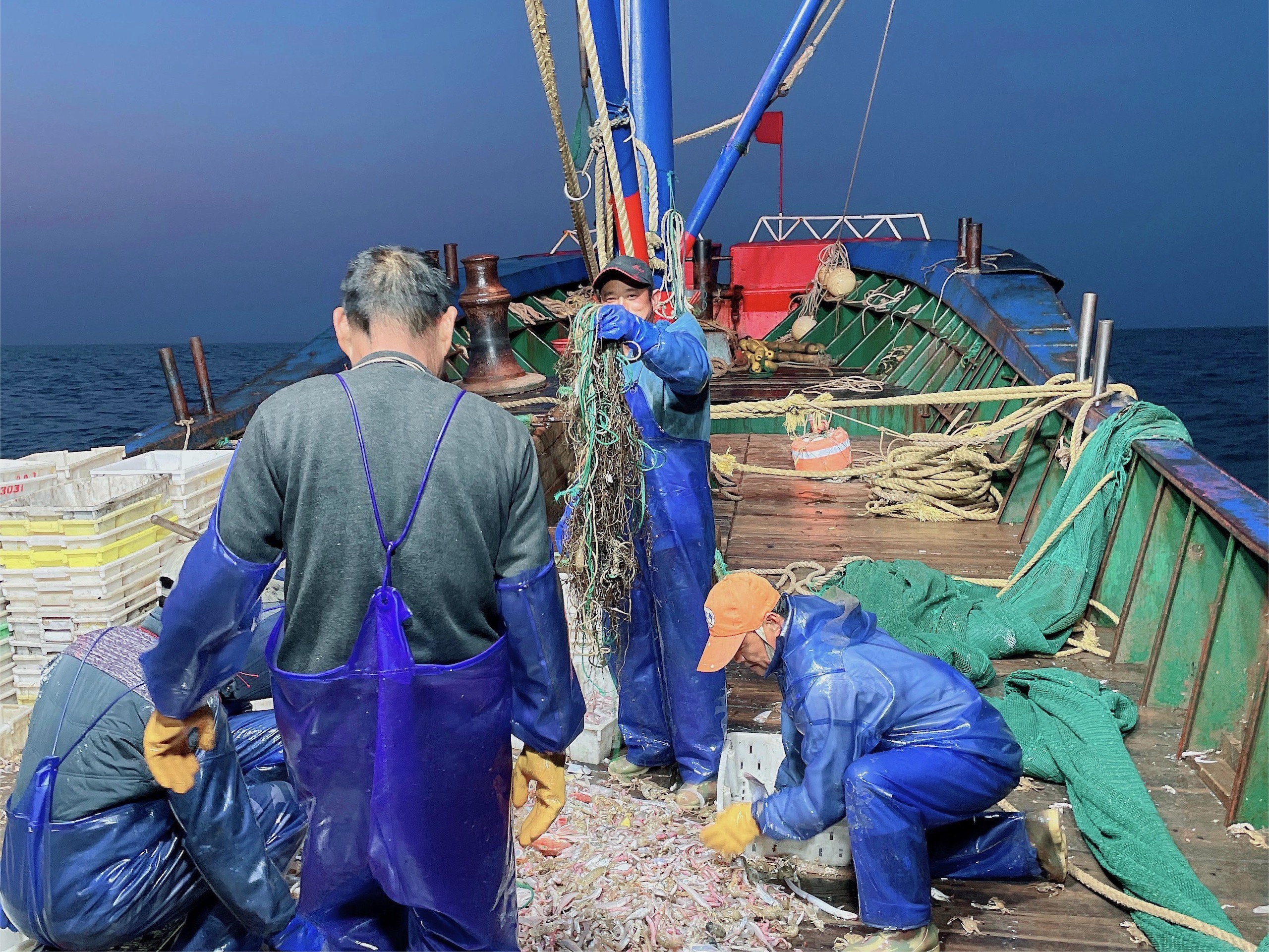 Several men aboard a boat, sorting out ghost gear and rubbish